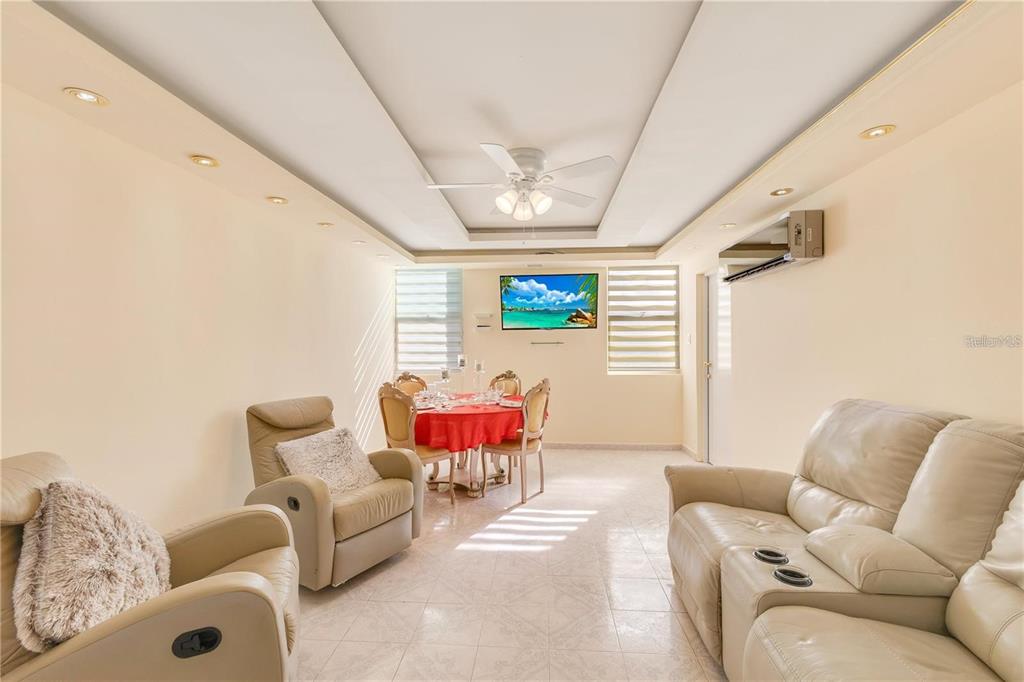 A living and dining area with light-colored tile floors, leather furniture, and a ceiling fan — 5890 JOSE M TARTAK AVE UNIT 704A, CAROLINA, PR