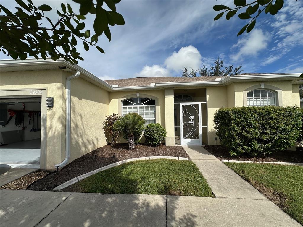 The exterior of a single-story house features a garage, a front entrance, and landscaping — 24308 WESTGATE BOULEVARD, PUNTA GORDA, FL