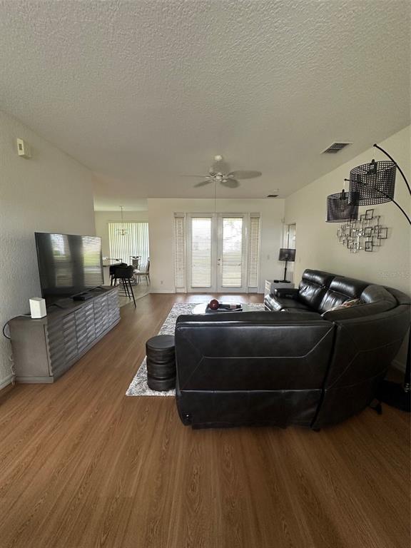 A living room features wood-look flooring, a large sectional sofa, and a television console — 24308 WESTGATE BOULEVARD, PUNTA GORDA, FL