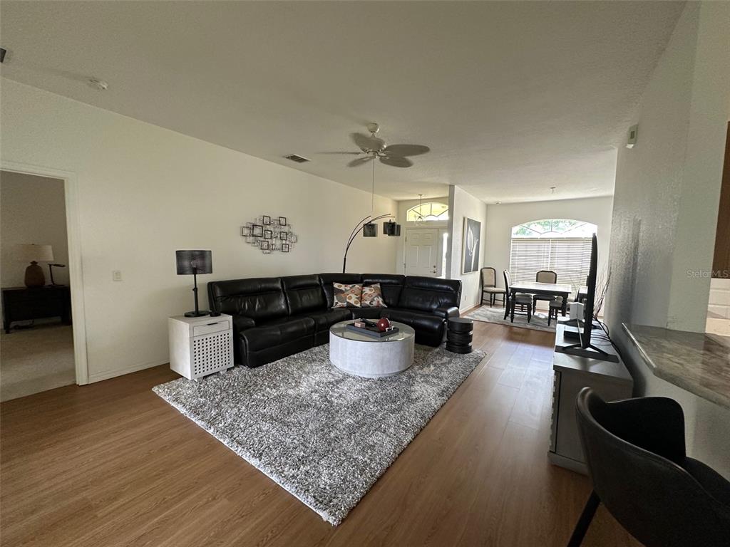 A living room features a black sectional sofa, a gray area rug, and wood-look flooring — 24308 WESTGATE BOULEVARD, PUNTA GORDA, FL