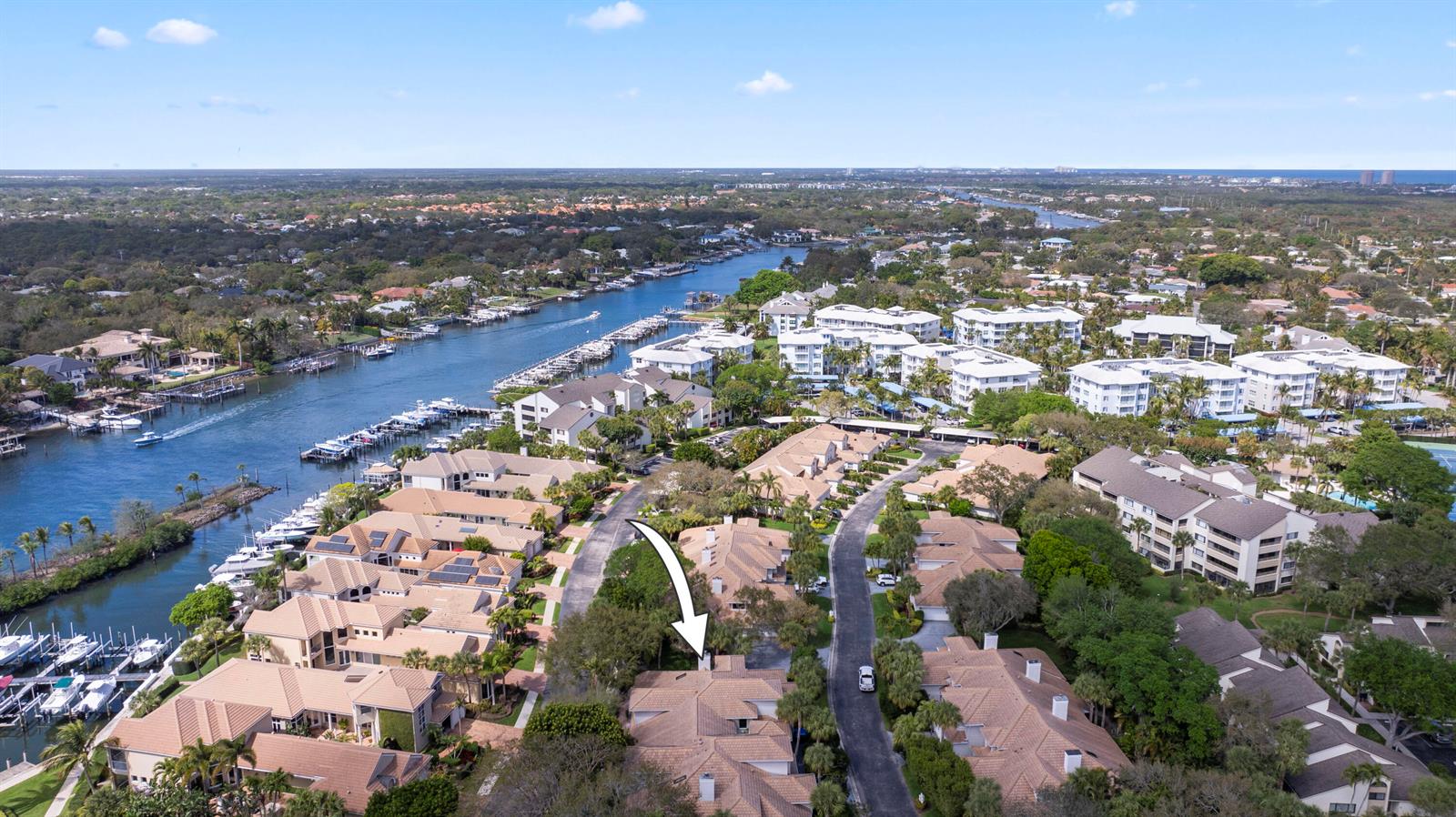 An aerial view shows a residential neighborhood with a canal, boat slips, and multi-family homes — 461 Coral Cove Drive, Juno Beach FL 33408, JUNO BEACH, FL