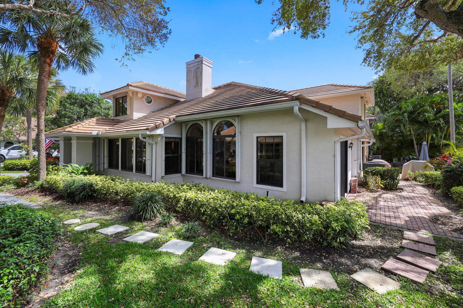 A beige two-story house with a tiled roof, arched windows, and a brick walkway — 461 Coral Cove Drive, Juno Beach FL 33408, JUNO BEACH, FL