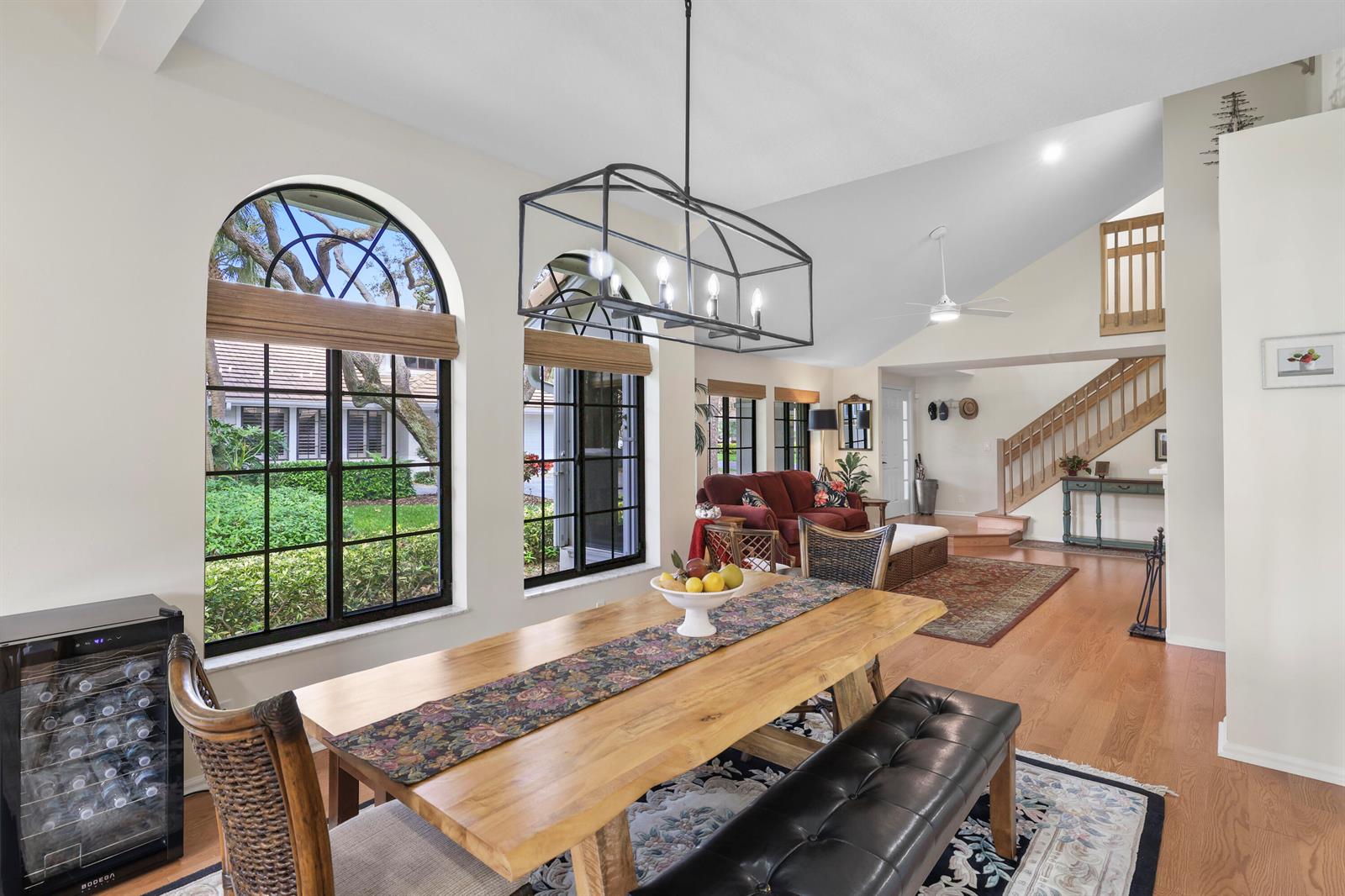 A dining area with a wooden table and black bench overlooks a living room staircase — 461 Coral Cove Drive, Juno Beach FL 33408, JUNO BEACH, FL