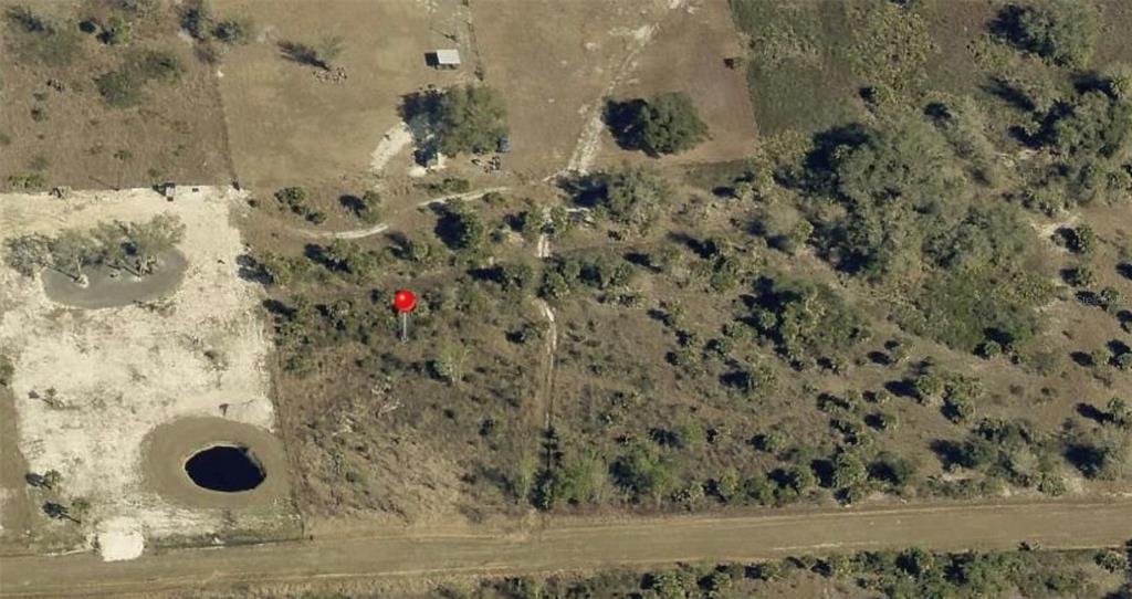 This aerial view shows a rural lot featuring a large sinkhole and a red marker — 20275 NW 284TH STREET, OKEECHOBEE, FL