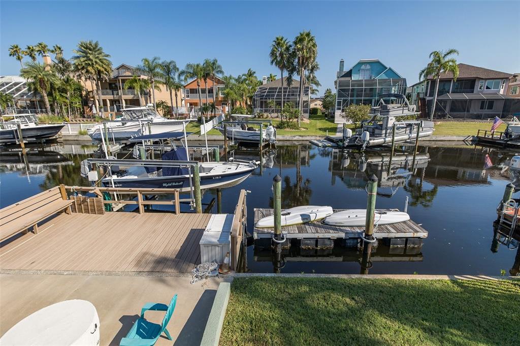 A canal view features a wooden dock with kayaks, several boats, and waterfront houses — 4335 SANDDOLLAR COURT, NEW PORT RICHEY, FL