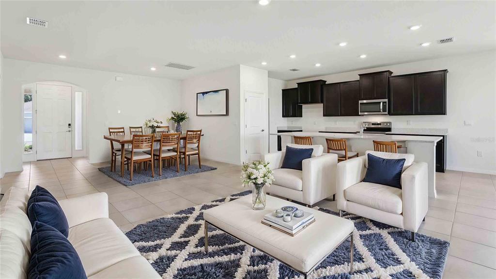 An open-concept living room and kitchen featuring white tile floors and dark wood cabinetry — 8172 IVES PLACE, WILDWOOD, FL
