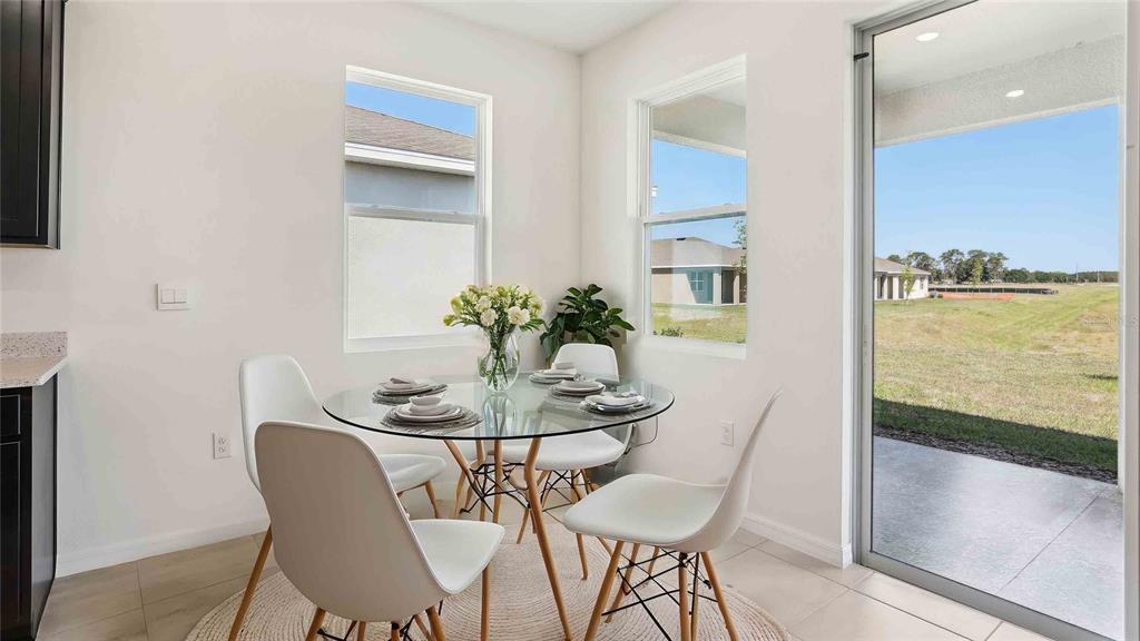 A dining area with a glass table, four white chairs, and a sliding glass door — 8172 IVES PLACE, WILDWOOD, FL