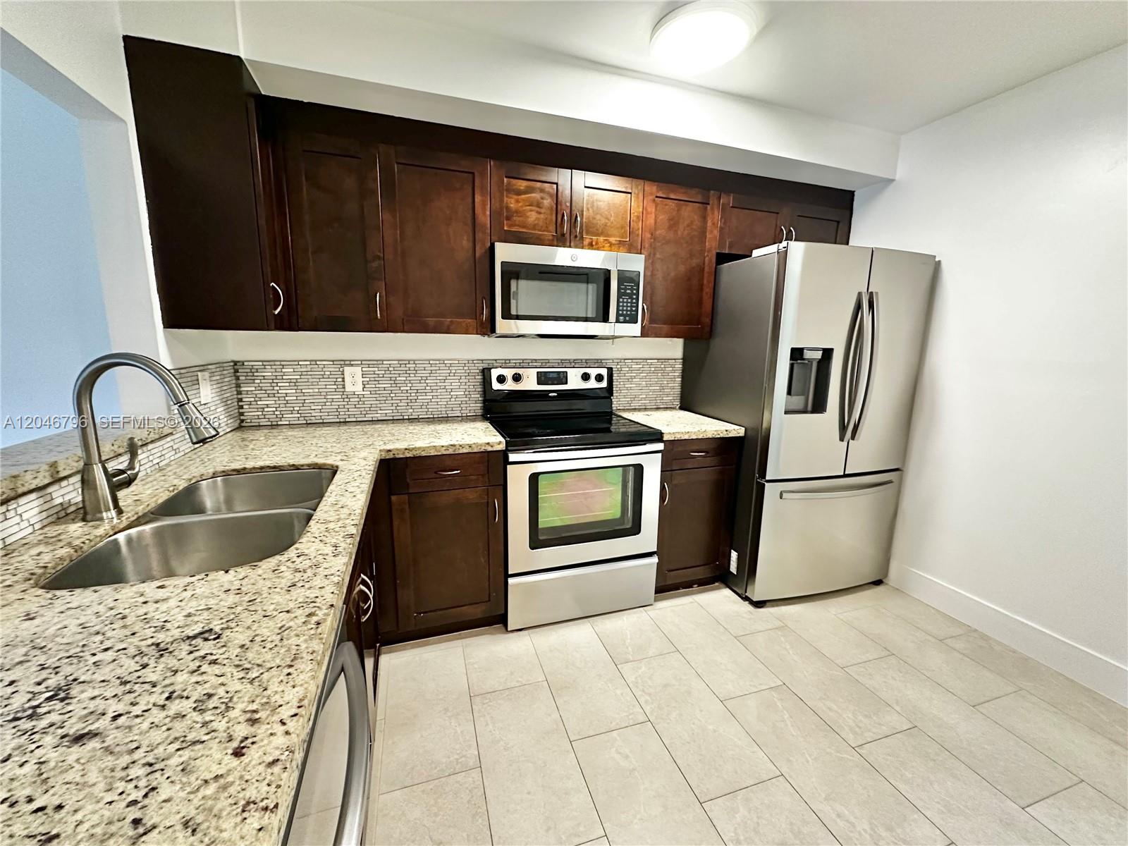 A kitchen features dark wood cabinets, granite countertops, stainless steel appliances, and tiled flooring — 4245 S Pine Island Rd, Davie FL 33328, DAVIE, FL