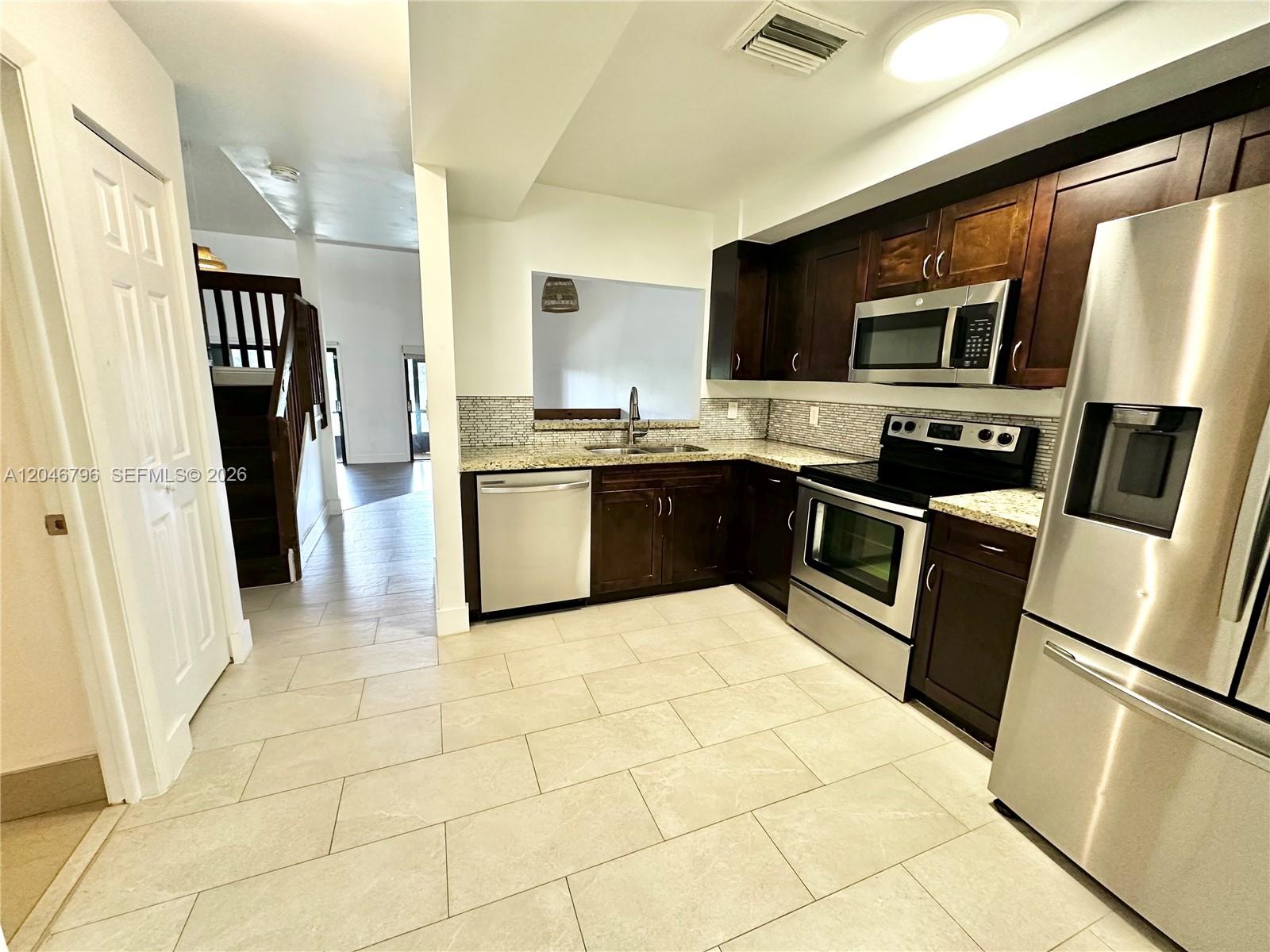 A kitchen features dark wood cabinets, stainless steel appliances, and light-colored tile flooring — 4245 S Pine Island Rd, Davie FL 33328, DAVIE, FL