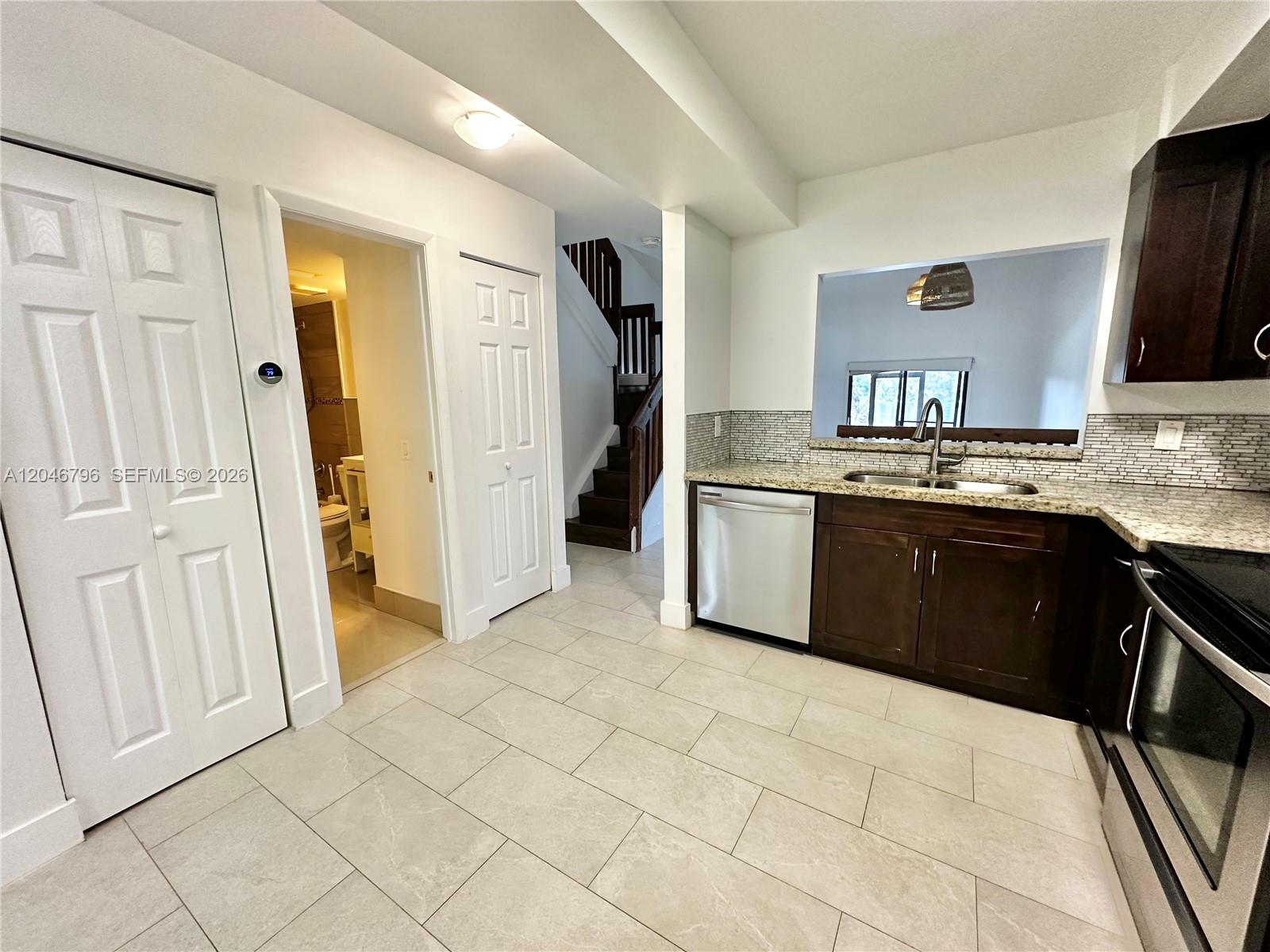 A kitchen with dark wood cabinets, granite countertops, and a view into another room — 4245 S Pine Island Rd, Davie FL 33328, DAVIE, FL