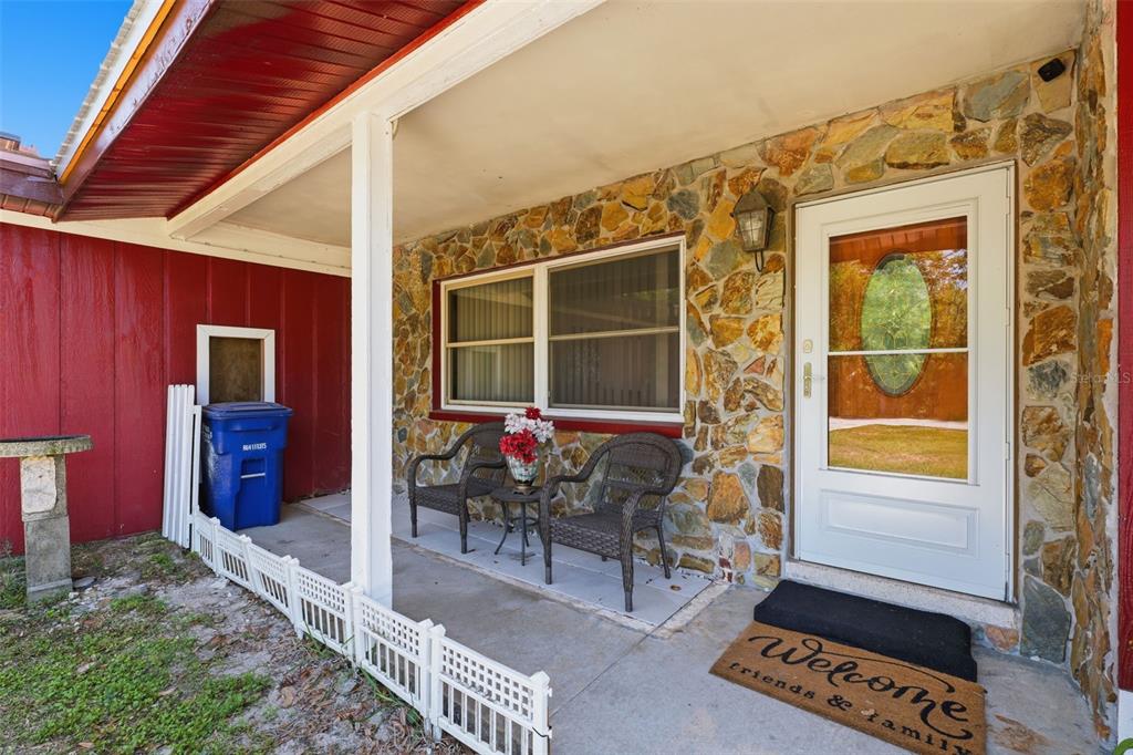 A covered front porch features a stone facade, two wicker chairs, and a white door — 764 NE 13TH STREET, CRYSTAL RIVER, FL