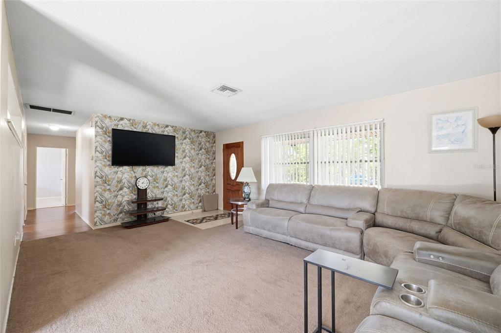 A living room features a large sectional sofa, patterned wallpaper, and a wall-mounted television — 764 NE 13TH STREET, CRYSTAL RIVER, FL