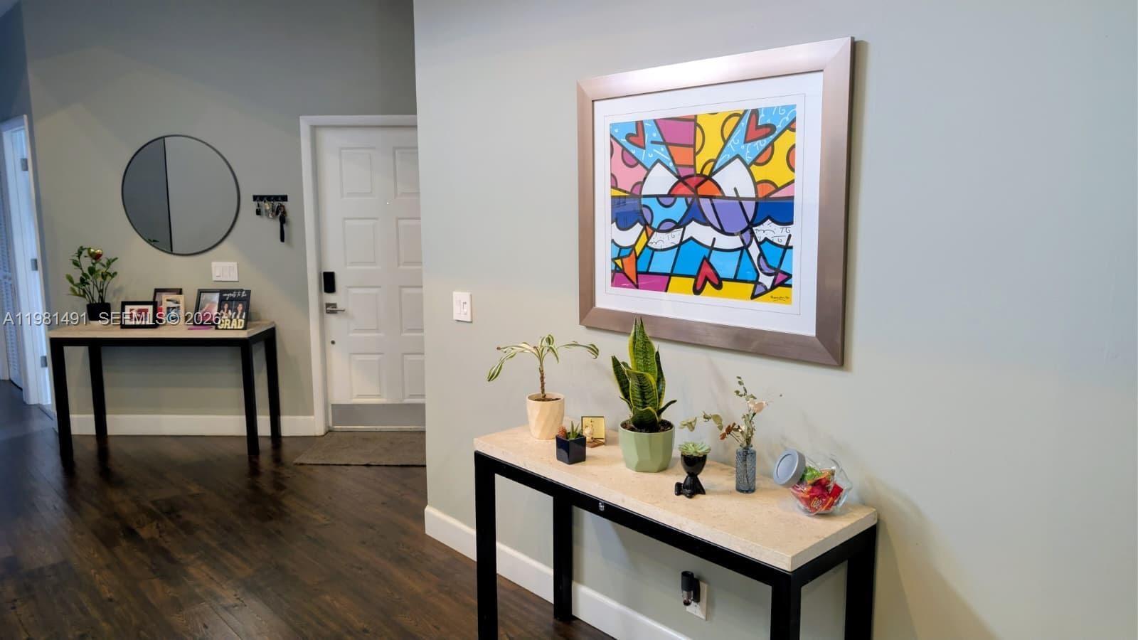 A brightly lit entryway features a console table, a colorful framed print, and dark flooring — 20478 Via Marisa, Boca Raton FL 33498, BOCA RATON, FL