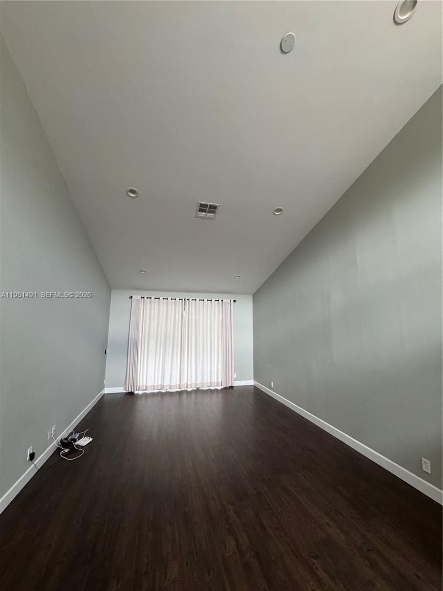 An empty room features dark wood flooring, light gray walls, and a large sliding glass door — 20478 Via Marisa, Boca Raton FL 33498, BOCA RATON, FL