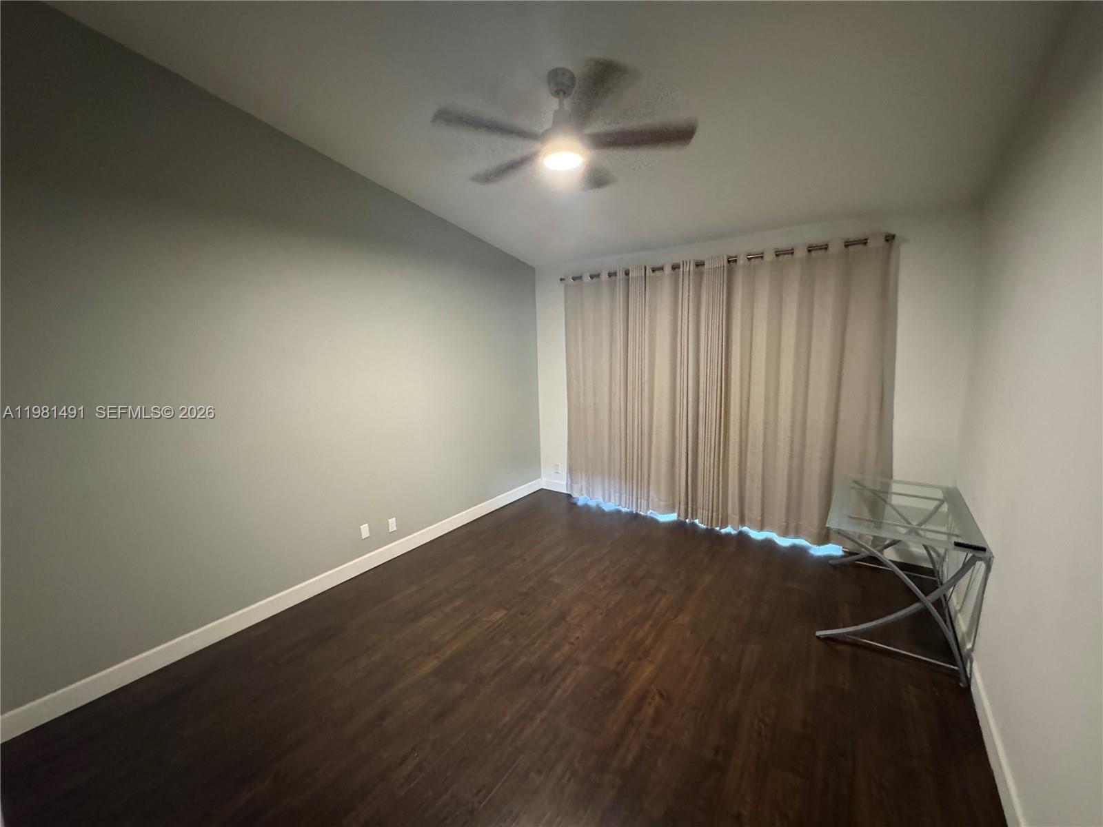 An empty room features dark wood flooring, a ceiling fan, and a glass desk — 20478 Via Marisa, Boca Raton FL 33498, BOCA RATON, FL