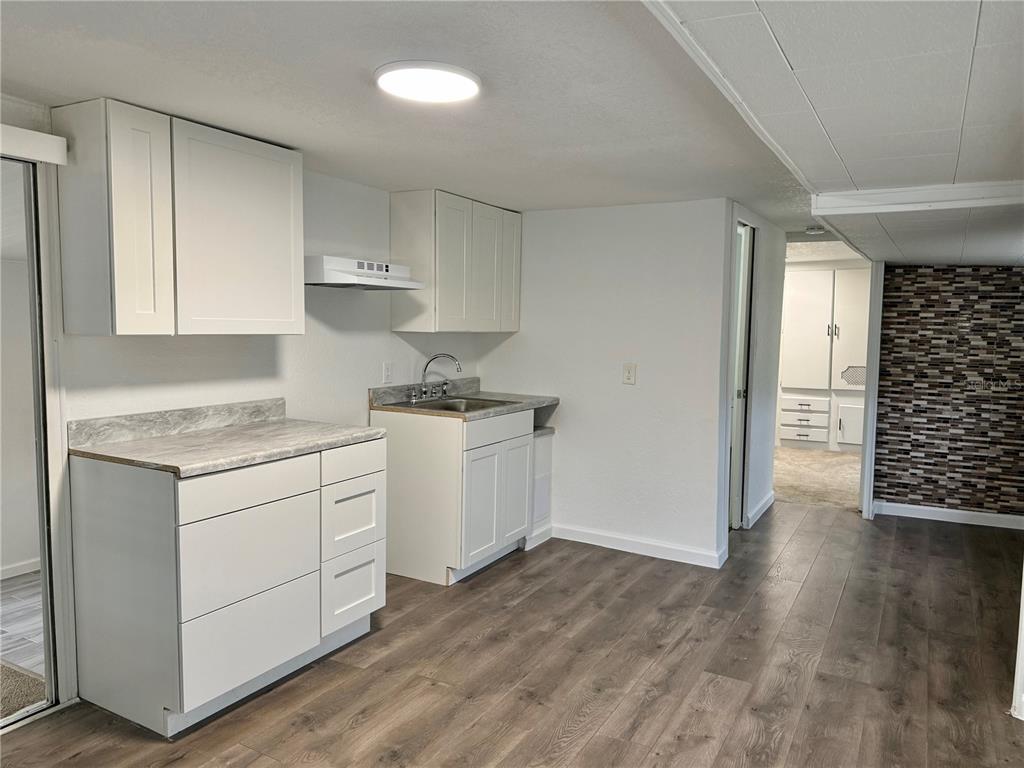 A kitchen features white cabinets, gray countertops, and wood-look flooring — 317 GOLF CREST LANE UNIT 58, DAVENPORT, FL