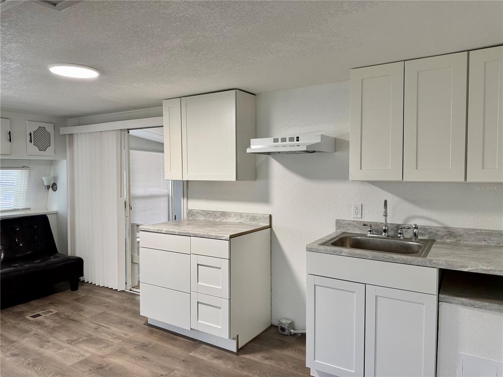 A kitchen features white cabinets, a stainless steel sink, and light-colored laminate countertops — 317 GOLF CREST LANE UNIT 58, DAVENPORT, FL