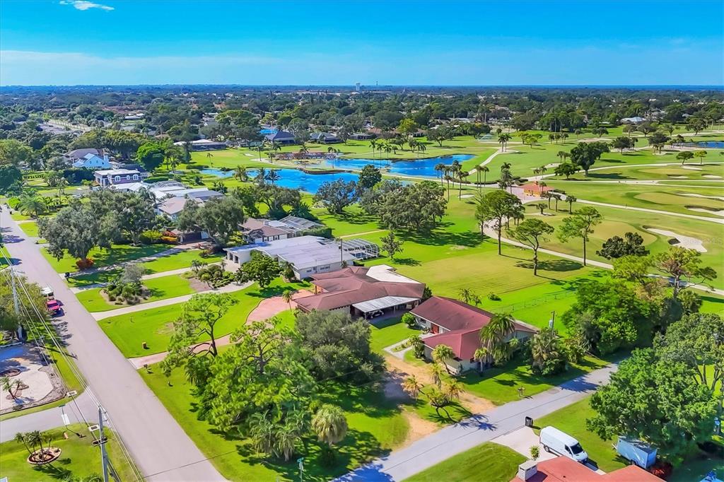 An aerial view shows houses situated along a golf course with a central pond — 4704 18TH AVENUE W, BRADENTON, FL