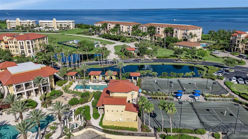 An aerial view shows a resort-style complex with swimming pools, tennis courts, and waterfront buildings — 99 VIVANTE BOULEVARD UNIT 9949, PUNTA GORDA, FL