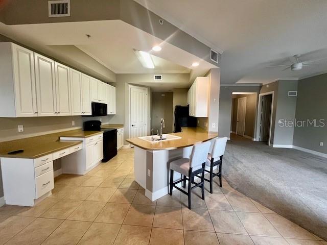 A kitchen features white cabinetry, a central island with bar stools, and tiled flooring — 99 VIVANTE BOULEVARD UNIT 9949, PUNTA GORDA, FL