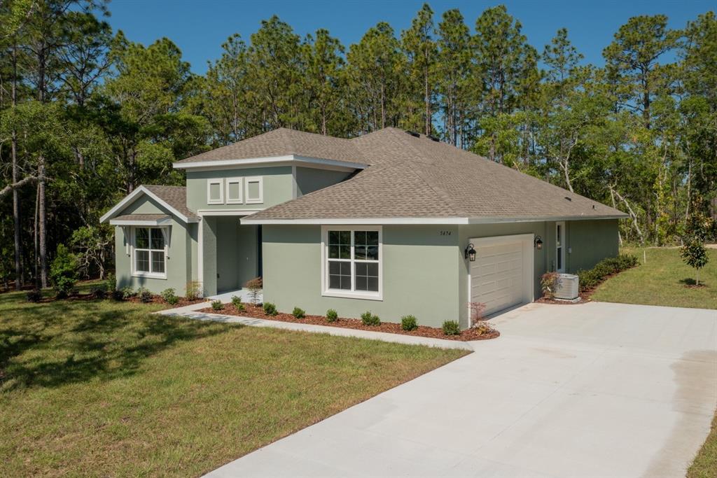 A light green single-story house with a two-car garage and a concrete driveway — 13454 SW 67TH LANE, OCALA, FL