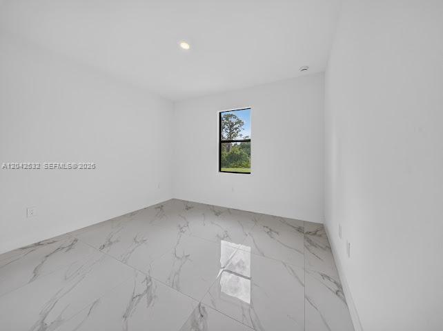 An empty room features white walls, a single window, and glossy white marble-patterned tile flooring — 928-930 Hepburn Ave, Lehigh Acres FL 33974, LEHIGH ACRES, FL