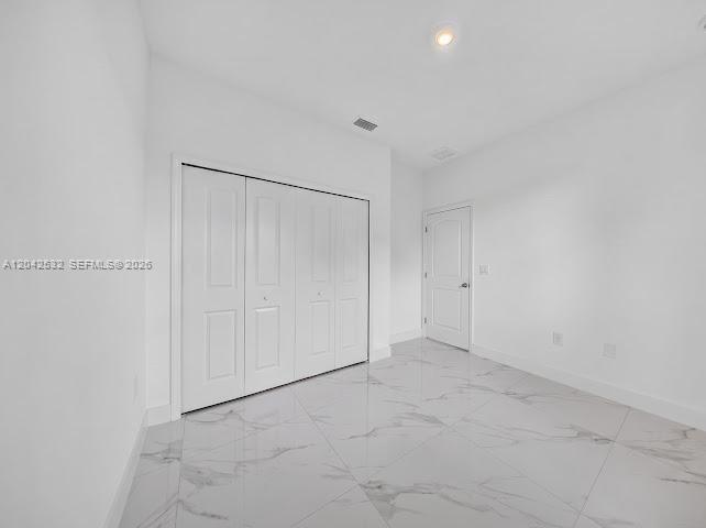 A room with white walls, a large closet with folding doors, and white marble-patterned tile flooring — 928-930 Hepburn Ave, Lehigh Acres FL 33974, LEHIGH ACRES, FL