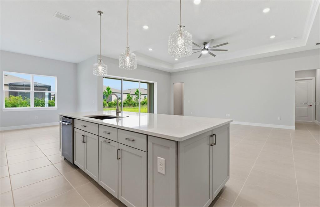 A kitchen island with light gray cabinets and quartz countertops sits in an open-concept room — 6200 SW 82ND TERRACE ROAD, OCALA, FL