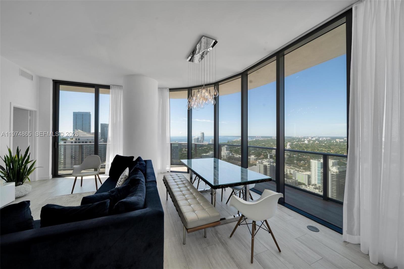 A modern dining and living area features floor-to-ceiling windows with panoramic city and water views — 55 SW 9th St # 4406, Miami FL 33130, MIAMI, FL