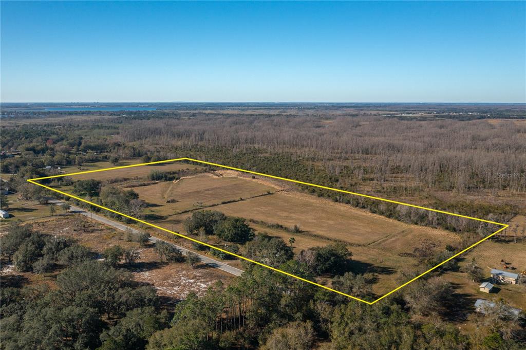 An aerial view shows a large, rectangular plot of cleared land outlined in yellow — 601 DIAMOND ACRES ROAD, DAVENPORT, FL