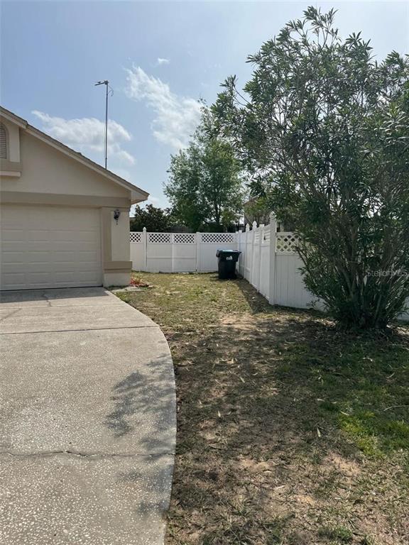 A concrete driveway leads to a house exterior with a white fence and a tree — 6724 CALLIE ROAD, ORLANDO, FL