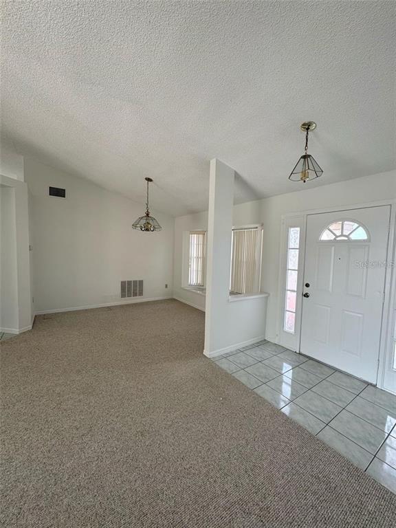 An entryway with tiled flooring leads into a carpeted living area with vaulted ceilings — 6724 CALLIE ROAD, ORLANDO, FL