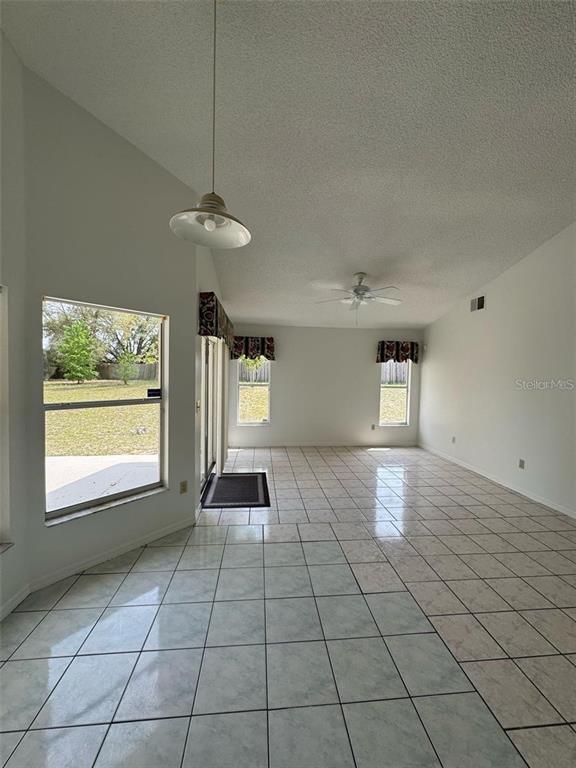 An open-concept room features light-colored tile flooring, a vaulted ceiling, and large windows — 6724 CALLIE ROAD, ORLANDO, FL