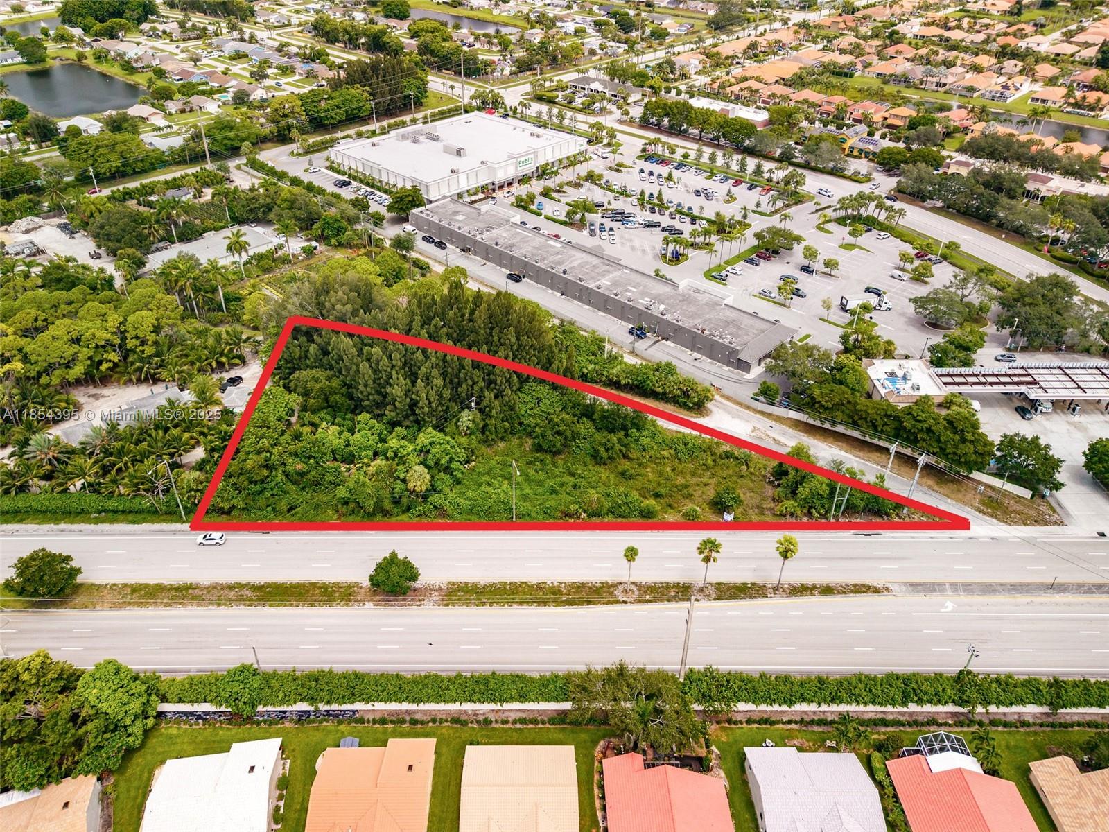 An aerial view shows a triangular, undeveloped wooded lot adjacent to a commercial shopping center — 8301 S Military Trl, Boynton Beach FL 33436, BOYNTON BEACH, FL