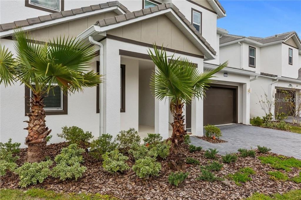 A two-story house exterior with a paved driveway, two palm trees, and a covered entryway — 2626 CALISTOGA AVENUE, KISSIMMEE, FL