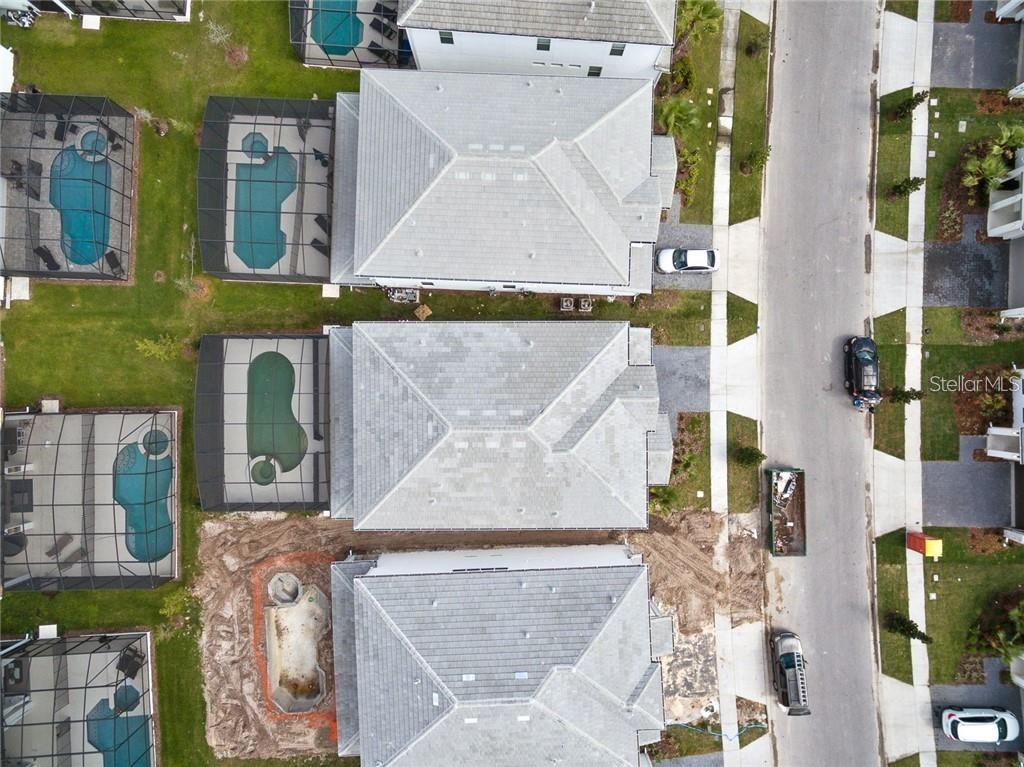 An aerial view shows three houses with swimming pools and screen enclosures along a street — 2626 CALISTOGA AVENUE, KISSIMMEE, FL