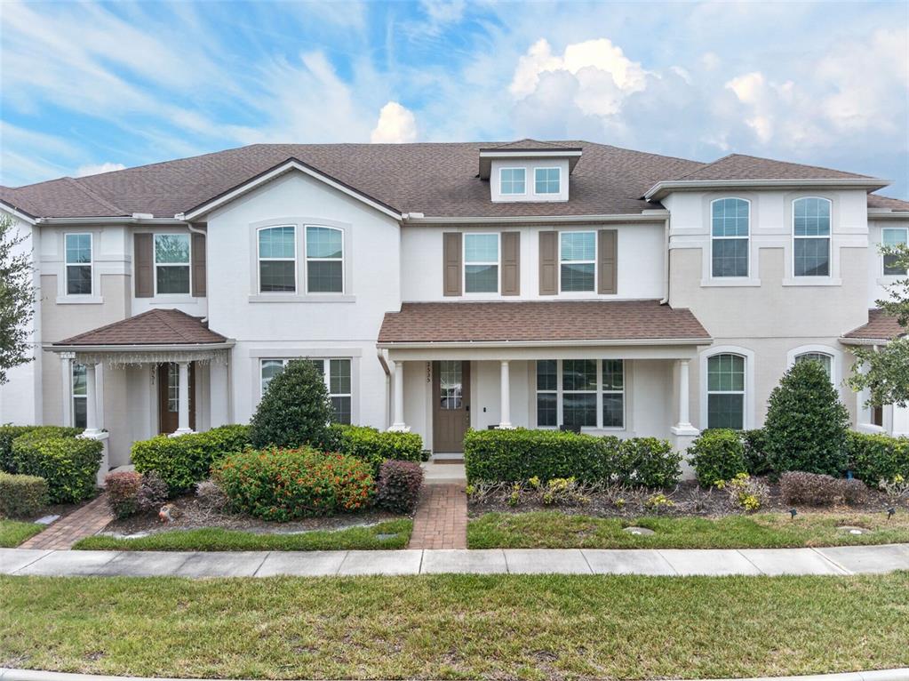 A two-story townhouse with a brown shingled roof, white stucco exterior, and landscaped front yard — 2535 FASSONA DRIVE, KISSIMMEE, FL