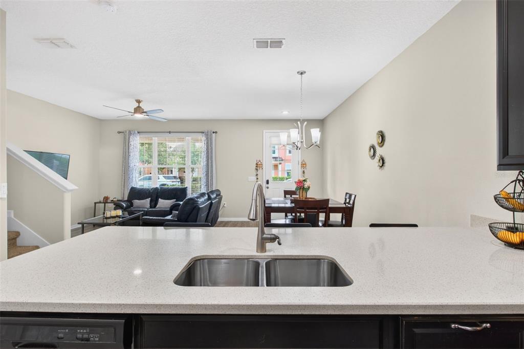 A kitchen island with a stainless steel sink overlooks an open-concept living and dining area — 2535 FASSONA DRIVE, KISSIMMEE, FL