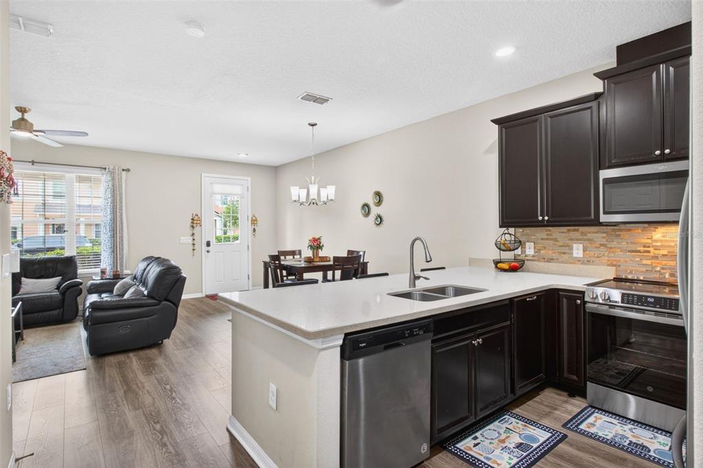 An open-concept kitchen with dark cabinets and a breakfast bar overlooks a dining area — 2535 FASSONA DRIVE, KISSIMMEE, FL