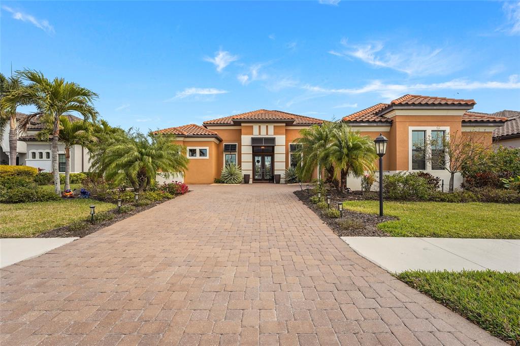 A single-story house with a paved driveway, terracotta roof, and orange stucco exterior — 12012 LEGACY ESTATES BOULEVARD, SARASOTA, FL