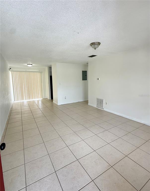 An empty room with light-colored floor tiles, white walls, and a sliding glass door — 2800 E 113TH AVENUE UNIT B4, TAMPA, FL