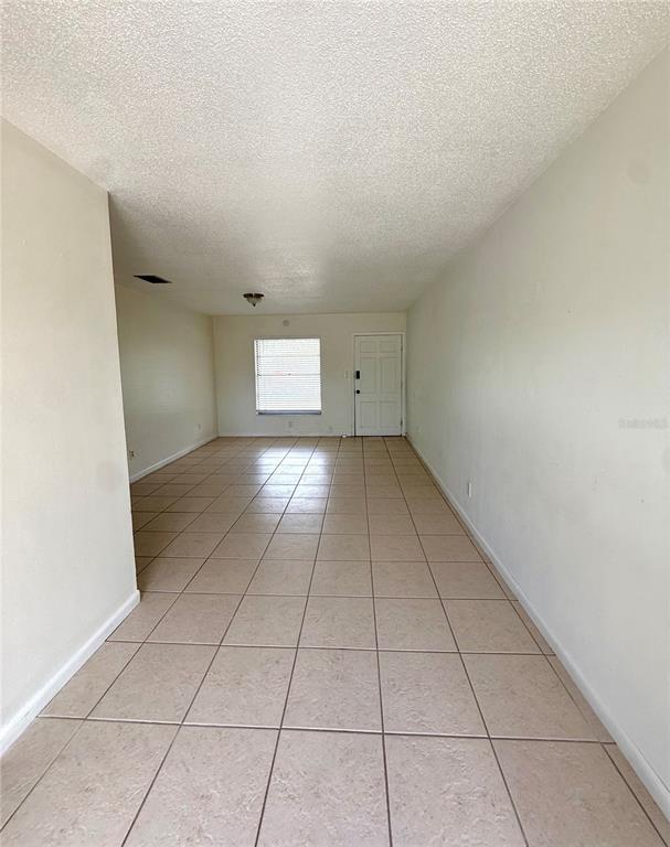 An empty room features light-colored tile flooring, plain white walls, and a single window — 2800 E 113TH AVENUE UNIT B4, TAMPA, FL