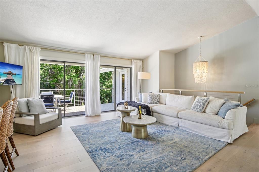A living room features a white sectional sofa, blue area rug, and sliding glass doors — 3390 BAYOU SOUND, LONGBOAT KEY, FL