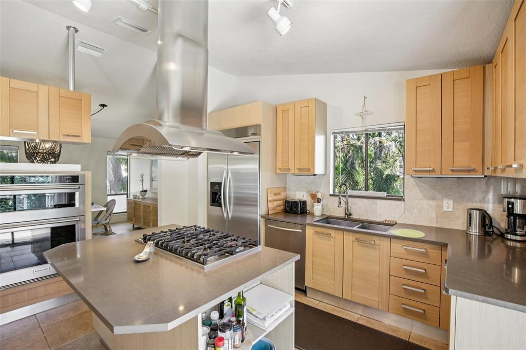 A kitchen features light wood cabinets, stainless steel appliances, a center island, and stone countertops — 3390 BAYOU SOUND, LONGBOAT KEY, FL