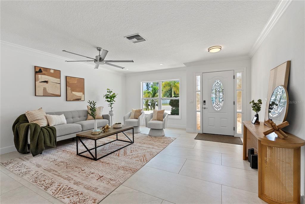 A bright living room features a gray sofa, two accent chairs, and a patterned area rug — 805 LEISEY CIRCLE, RUSKIN, FL
