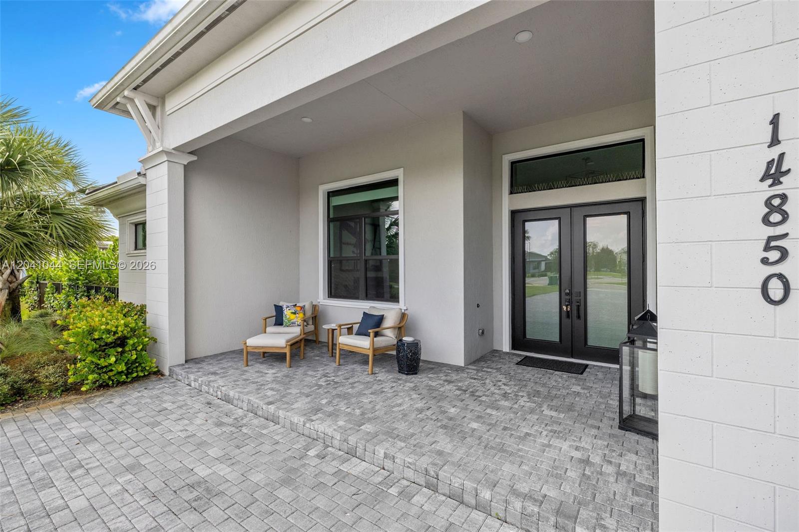A covered front porch features gray paver flooring, two wooden chairs, and a double-door entrance — 14850 Millstone Ranches Dr, Davie FL 33331, DAVIE, FL