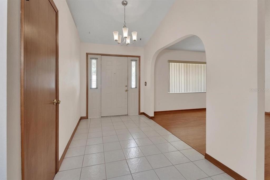 A tiled entryway features a white front door, a chandelier, and an arched doorway — 750 OAK TERRACE, ORANGE CITY, FL