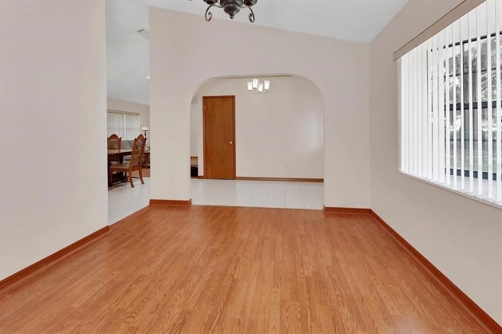 An interior view of a room with wood-look flooring and an arched entryway to another — 750 OAK TERRACE, ORANGE CITY, FL