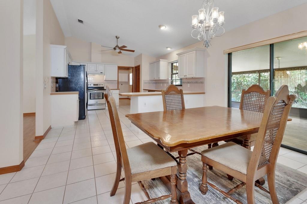 A dining area with a wooden table and chairs adjacent to a white kitchen — 750 OAK TERRACE, ORANGE CITY, FL