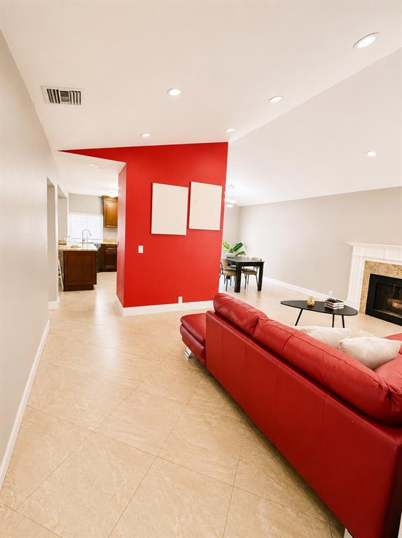 A living room with a red sofa, a red accent wall, and beige tile flooring — 17708 RIVENDEL ROAD, LUTZ, FL